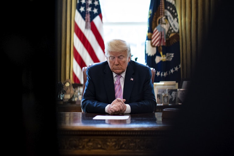 President Donald Trump bows his head in the Oval Office of the White House