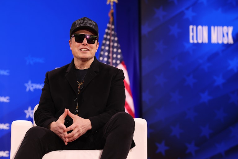Elon Musk sits onstage during CPAC