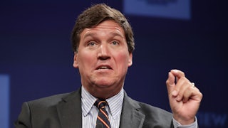 Fox News host Tucker Carlson gesticulates while speaking at an event.