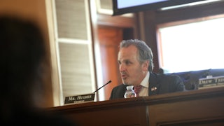 Bryan Hughes sits at a desk and speaks into a microphone.