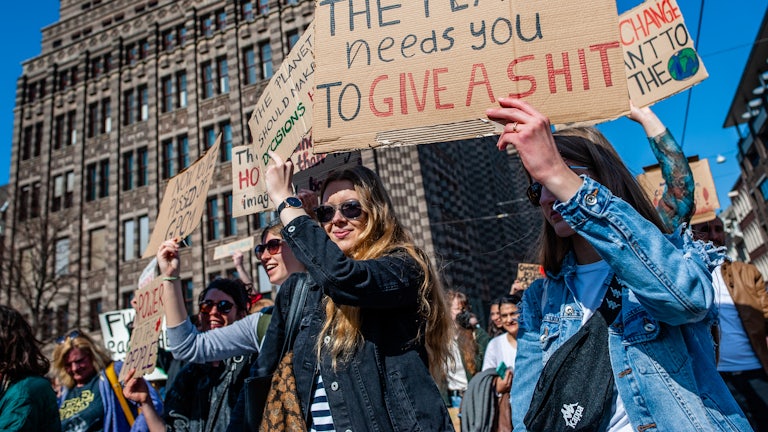 Protesters hold up signs, including one that reads: