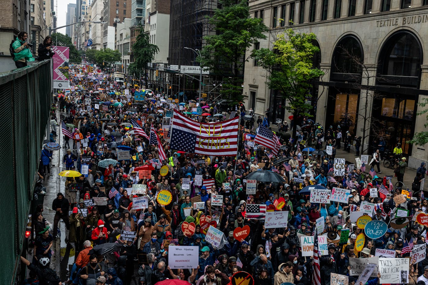 Thousands of people march during the “No Kings” protest in opposition of Donald Trump’s presidency on the day of the military parade, June 14, 2025, in New York, New York. A large upside down U.S. Flag says "No Kings."