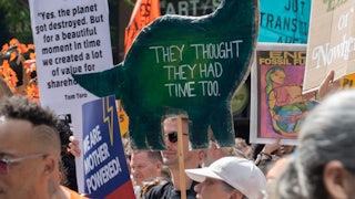 A sign shaped like a dinosaur reads "they thought they had time too."