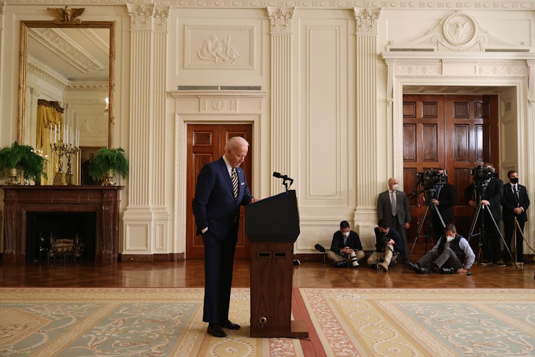 President Joe Biden stands behind a lectern, looking down at the floor.