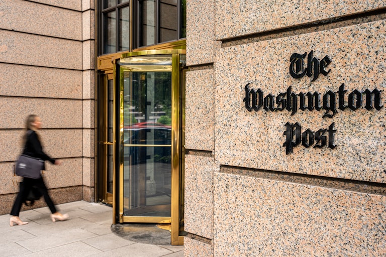 A person approaches the revolving doors of the Washington Post building