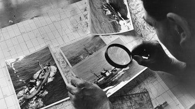 Examining photographs of a Soviet spy trawler taken during a reconnaissance flight over the Atlantic, 1968
