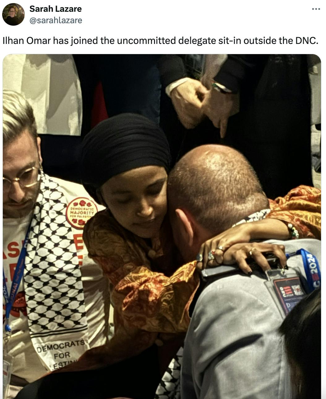 Twitter screenshot: Sarah Lazare @sarahlazare Ilhan Omar has joined the uncommitted delegate sit-in outside the DNC. (Photo of Ilhan Omar holding a man as he rests his head on her shoulder, perhaps crying)