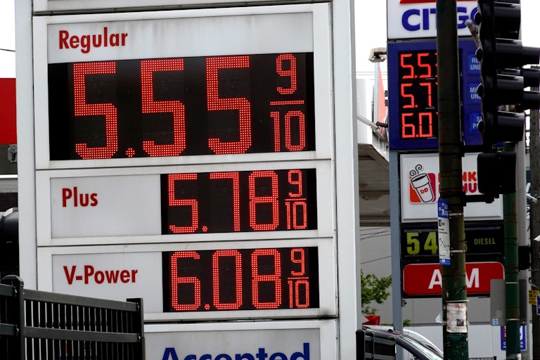 A sign displays gas prices, with "Regular" price being $5.55 9/10.