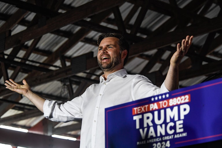 J.D. Vance stands with his arms up during a Donald Trump rally.
