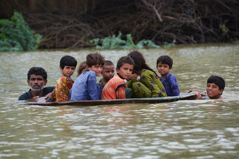 A man uses a satellite dish to move children across a flooded area after heavy monsoon rainfalls in Balochistan, Pakistan