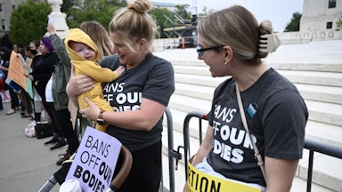 Two pro-choice demonstrators talk, as one holds a baby.