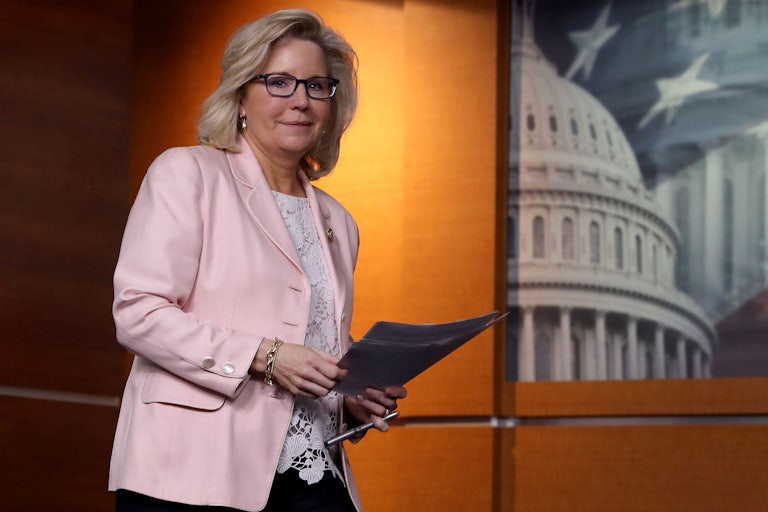 A smirking Liz Cheney carries papers through the U.S. Capitol.