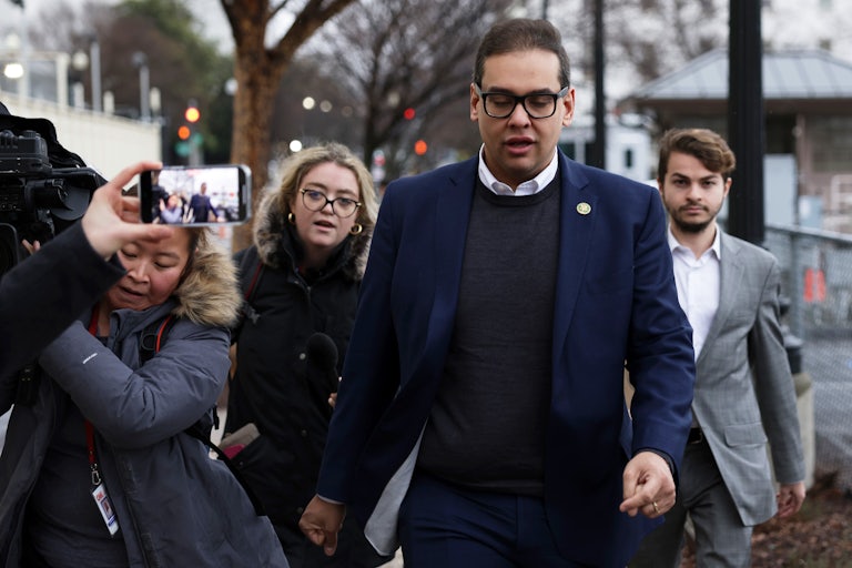 George Santos walks outside as several reporters follow him
