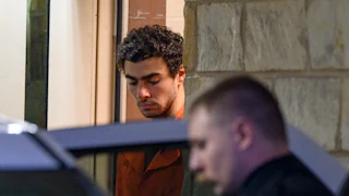 Luigi Mangione looks down while exiting a courthouse