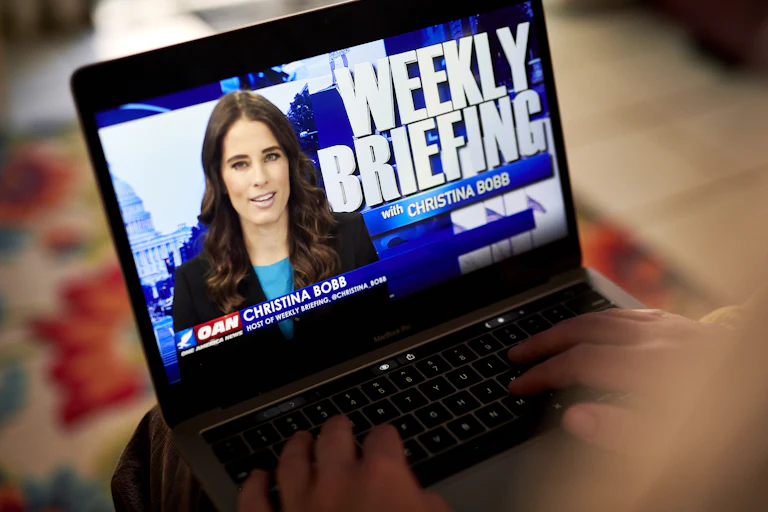The One America Nes Network Weekly Briefing with Christina Bobb shown playing on a laptop