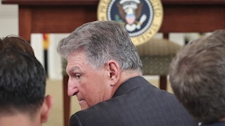 Senator Joe Manchin talks to others, facing away from the camera.