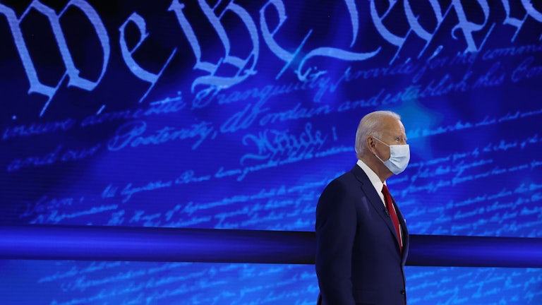 Joe Biden stands in front of a background reading “We the People.”