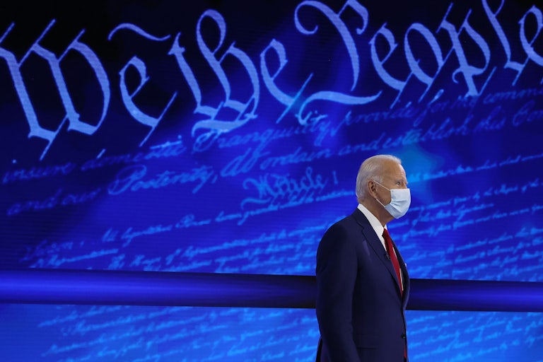 Joe Biden stands in front of a background reading “We the People.”