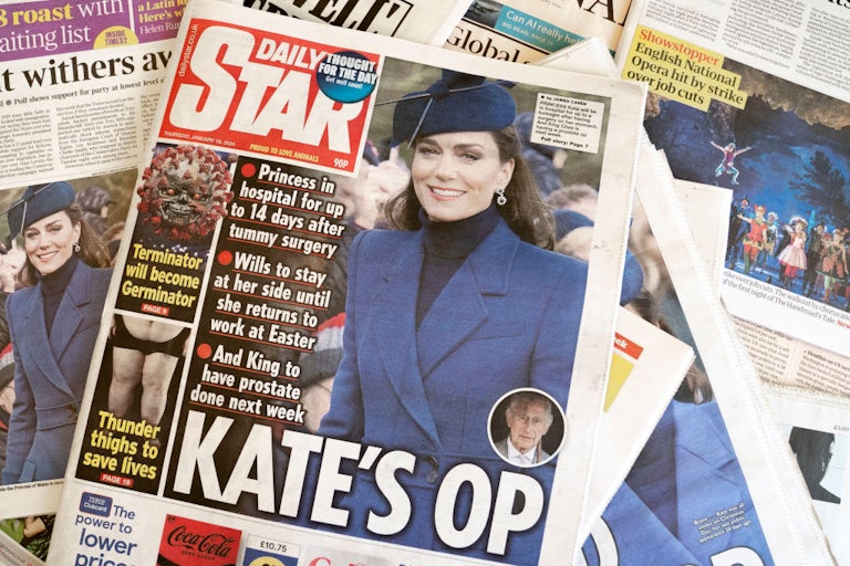Newspapers lie on top of one another showing front-page stories about Kate Middleton.