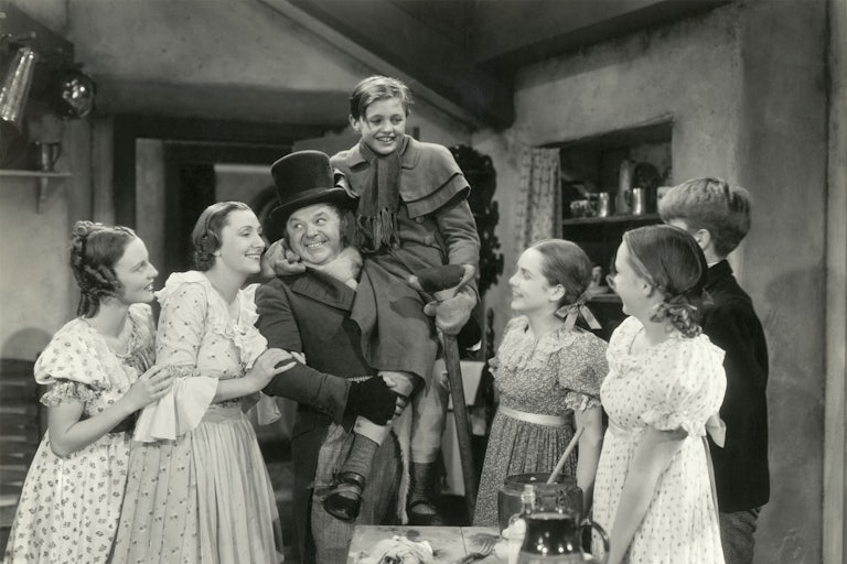 In this scene from the 1938 motion picture A Christmas Carol, Bob Cratchit hoists Tiny Tim in the air as his family looks on..