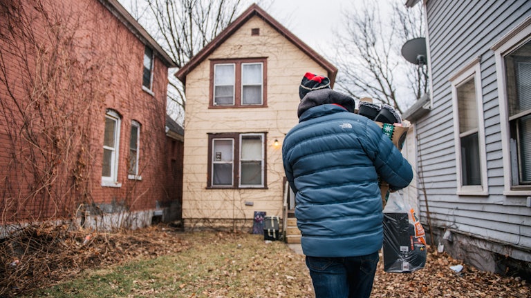 a man carries a bag of gifts to a home in St. Paul, Minnesota.