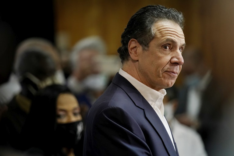 A close up of Andrew Cuomo in profile, staring down at a crowd.