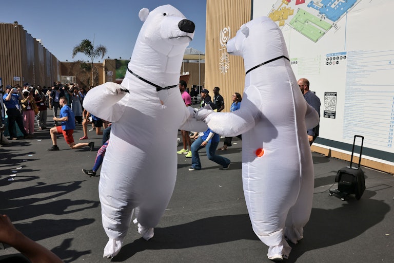 Two people in polar bear suits hold hands while dancing.