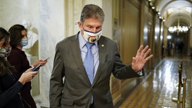 A masked Joe Manchin passes by reporters as he departs Capitol Hill.