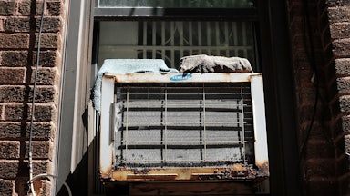 A rusty air conditioner sits in a window.