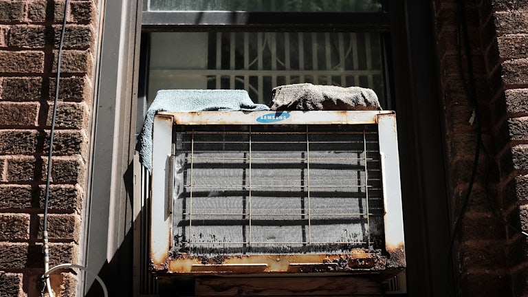 A rusty air conditioner sits in a window.