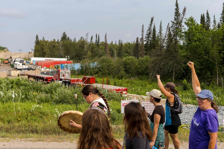 People raise their fists in front of a construction site.