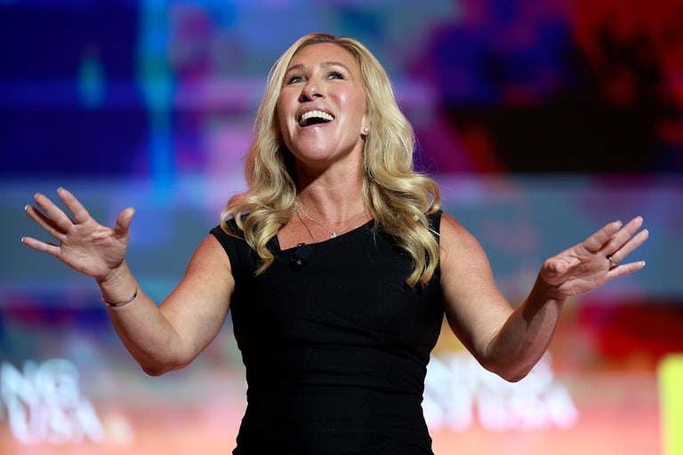 Marjorie Taylor Greene holds her arms out while smiling.