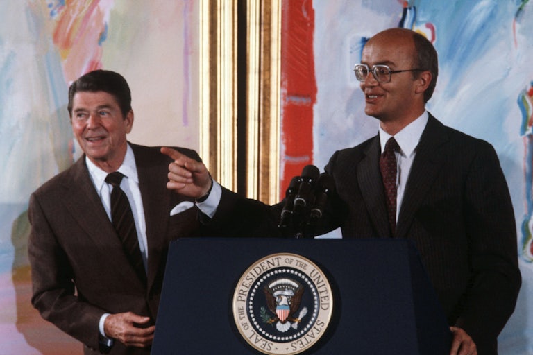 President Ronald Reagan stands next to Secretary of Interior James Watt at a podium.