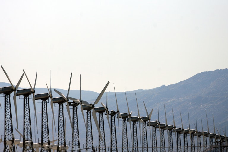 A row of wind turbines with hills in the background