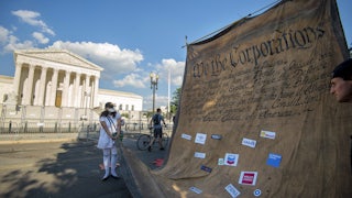 Climate activists carry a giant model of the constitution, altered to say "We The Corporations," in front of the Supreme Court building in Washington, D.C.