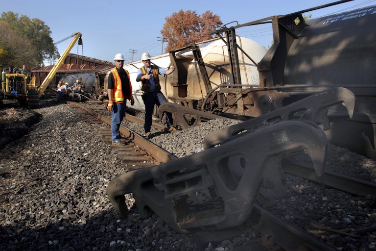 Workers standnear a derailed train