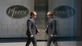A mirror creates the illusion that a man in a suit is walking into and out of Pfizer's headquarters.