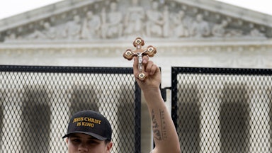 A pro-life demonstrator holds a cross near the unscalable fence that was erected around the US Supreme Court.