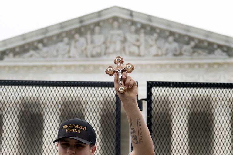 A pro-life demonstrator holds a cross near the unscalable fence that was erected around the US Supreme Court.