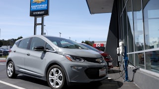 A Chevrolet Bolt sits in front of a charging station.
