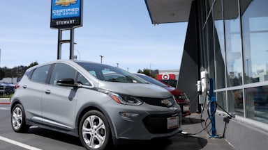A Chevrolet Bolt sits in front of a charging station.