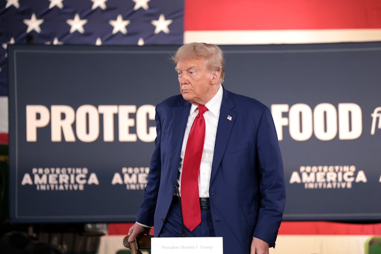 Donald Trump stands at a table during a campaign