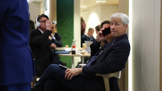 Jamie Dimon talks into a cell phone while seated.