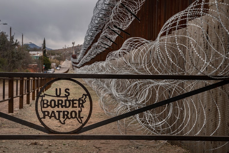 A barbed wire fence marked with the US Border Patrol sign at the US-Mexico border in Nogales, Arizona