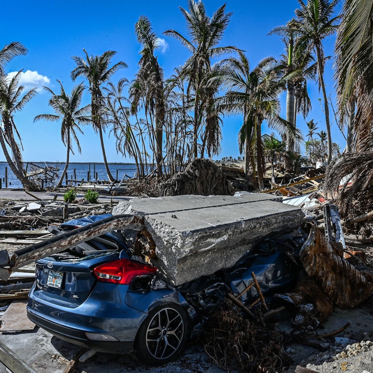 A piece of concrete lies on a crushed car amid wreckage from the hurricane.