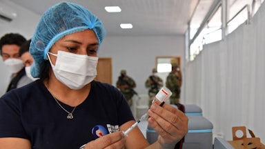 A nurse fills a syringe from a vial.