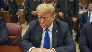 Donald Trump looks down while sitting in court for his hush-money trial