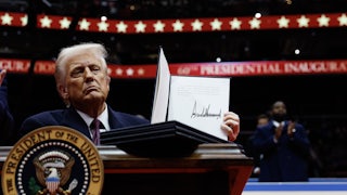 Donald Trump holds up a signed executive order during his inaugural parade