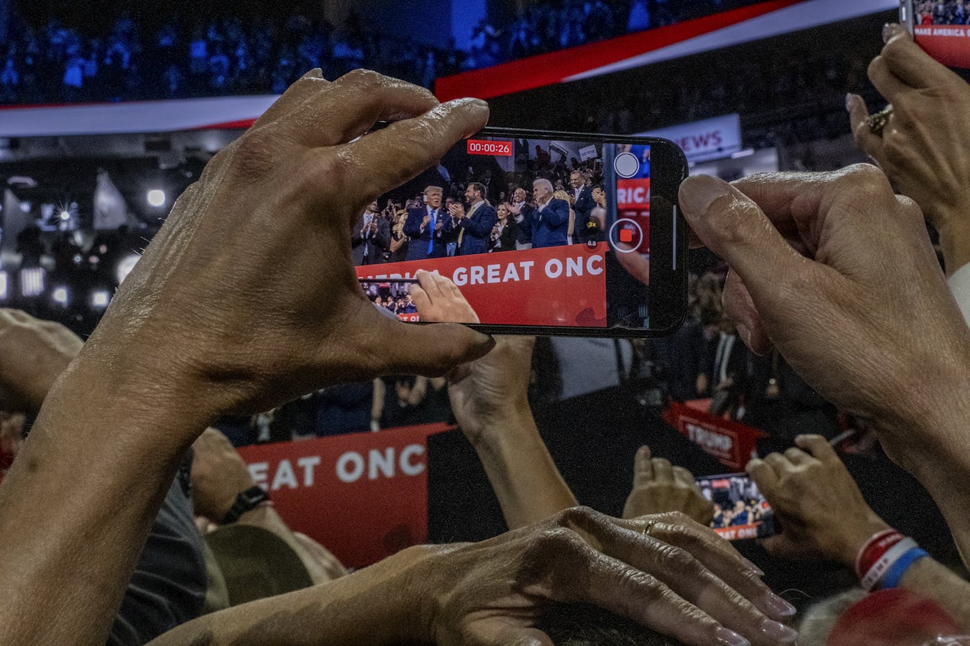 A photograph of a person recording Donald Trump with a phone while at the Republication National Convention 