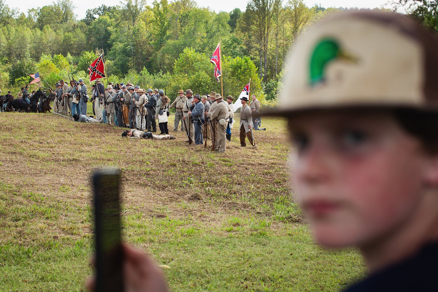 A young boy in the foreground watches Confederate reenactors.